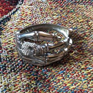 Bejeweled skull on skeleton hand bracelet